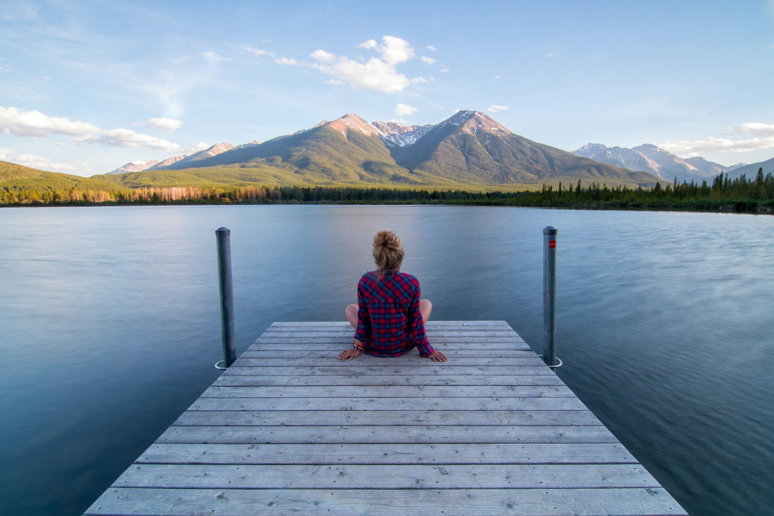 view our terms of business - woman at a lake admiring the view while sitting on a dock