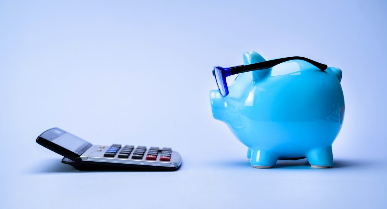 A calculator and a piggy bank holding emergency cash savings